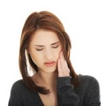 Teen woman pressing her bruised cheek with a painful expression as if she's having a terrible tooth ache.