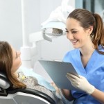 Dentist holding a medical history asking information to a patient before treatment sitting on a chair in a clinic box