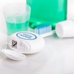 Dental floss focused with  toothbrush, toothpaste, mouthwash, at background, essential oral care products recommended by dentist.