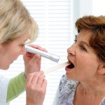 Doctor examines senior woman for sore throat