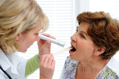 Doctor examines senior woman for sore throat