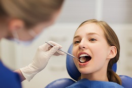 people, medicine, stomatology and health care concept - happy female dentist with mirror checking patient girl teeth up at dental clinic office